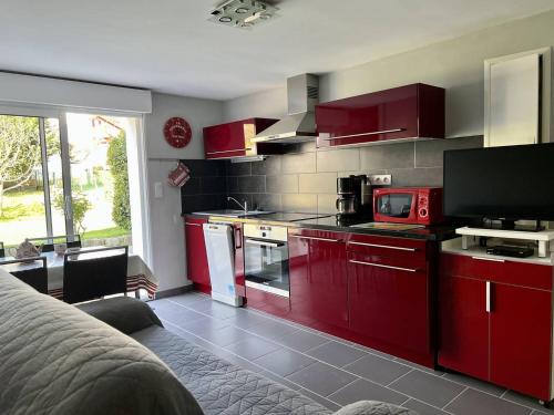 - une cuisine équipée de placards rouges et d'un four micro-ondes rouge dans l'établissement Rez-de-jardin rénové avec terrasse à Cambo-les-Bains, T1 Bis pour 2 personnes, équipé et lumineux - FR-1-495-93, à Cambo-les-Bains