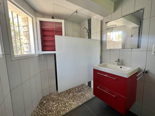 La salle de bains est pourvue d'une armoire rouge et d'un lavabo. dans l'établissement Rez-de-jardin rénové avec terrasse à Cambo-les-Bains, T1 Bis pour 2 personnes, équipé et lumineux - FR-1-495-93, à Cambo-les-Bains