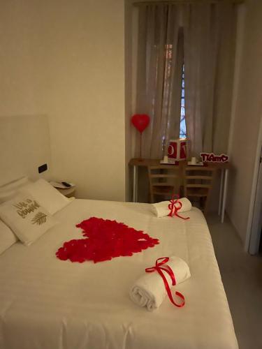 a white bed with a red flower on it at Costantino Home in Pompei