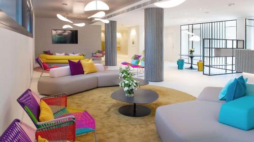 uma sala de estar com sofás, uma mesa e cadeiras em Hotel President em Lignano Sabbiadoro