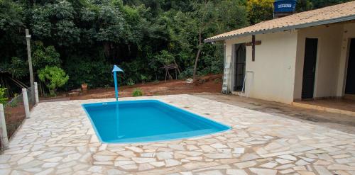 - une piscine bleue dans une cour à côté d'une maison dans l'établissement Chacara com piscina e lazer em Jaboticatubas MG, à Jaboticatubas