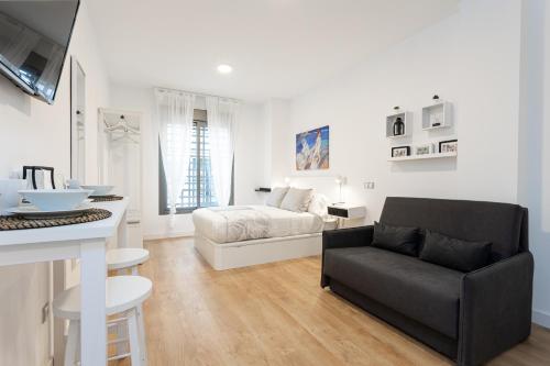 a white bedroom with a bed and a couch at Apartments Holidays2Malaga City Center in Málaga