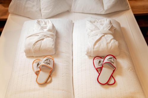 a bed with two towels and two pairs of slippers at Hotel Chalet Sas Morin in Pozza di Fassa