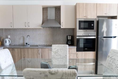 a kitchen with white cabinets and a glass table at Diwani Luxury Villas in Lixouri