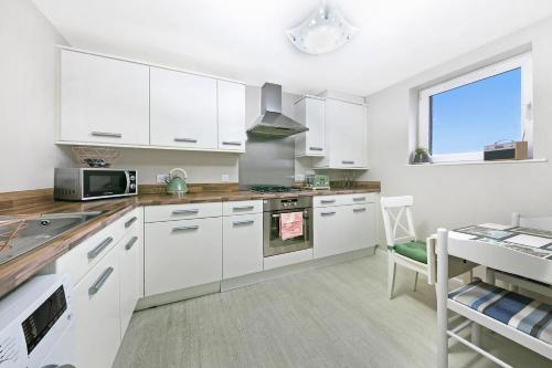 a kitchen with white cabinets and a microwave and a table at Kings Lodge - Grampian Lettings Ltd in Aberdeen