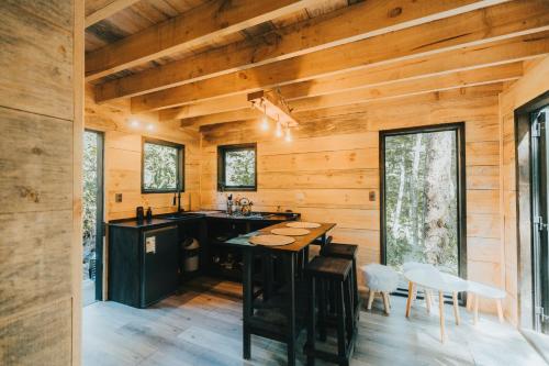a kitchen in a log cabin with a wooden ceiling at RUKAKUTRAL refugio de bosque in Pucón