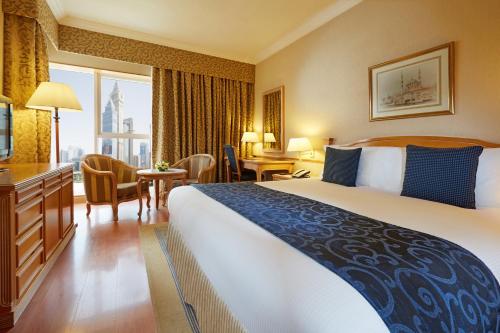 a hotel room with a large bed and a desk at Millennium Plaza Downtown, Dubai in Dubai