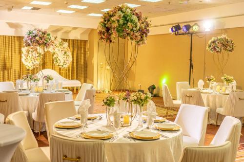 a banquet hall with white tables and chairs and flowers at Millennium Plaza Downtown, Dubai in Dubai