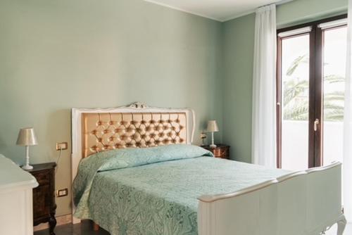 a bedroom with a bed with a green comforter and a window at B&B Domus Aurea 20 in San Giovanni Teatino