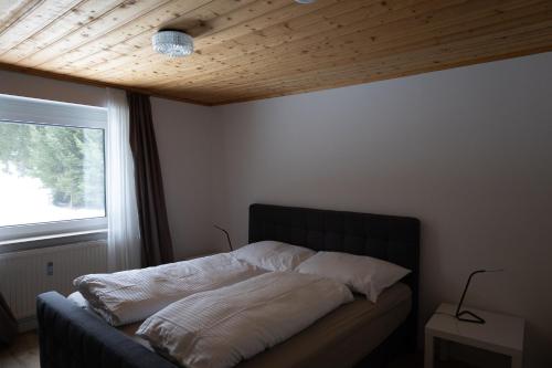 a bed sitting in a room with a window at L&P Appartement Gerlitzen & Pool - Haus Enzian in Kanzelhöhe
