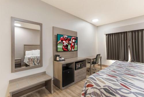a hotel room with a bed and a desk and a mirror at Red Roof Inn & Suites Corbin in Corbin