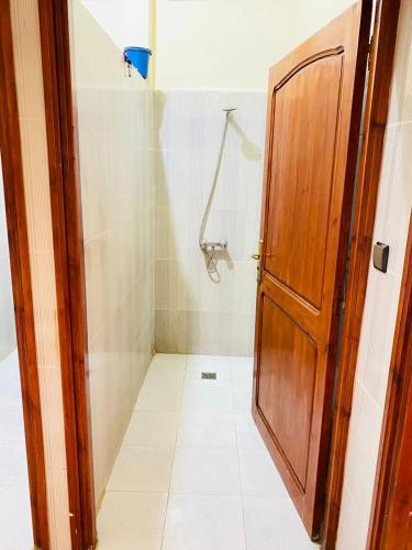 a bathroom with a shower and a wooden door at Sea Surf House Imsouane in Imsouane