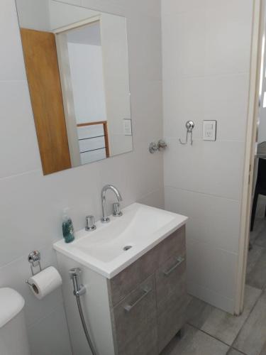 a white bathroom with a sink and a mirror at Aires de la costa Renovado in Neuquén