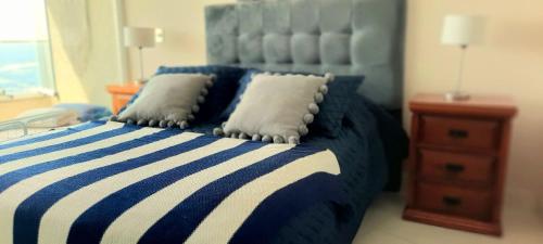 un letto blu e bianco con due cuscini sopra di Hermoso depto en borde costero Borgoño a Concón