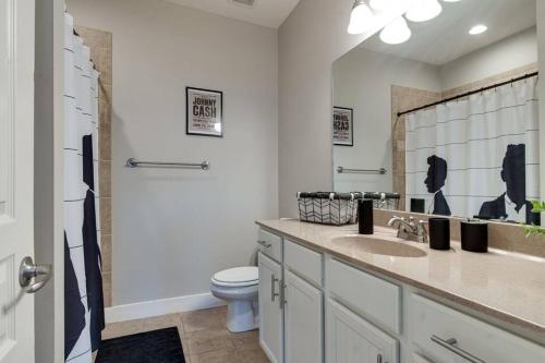 a bathroom with a sink and a toilet and a mirror at Cashville - Stylish Condo Minutes from Broadway in Nashville