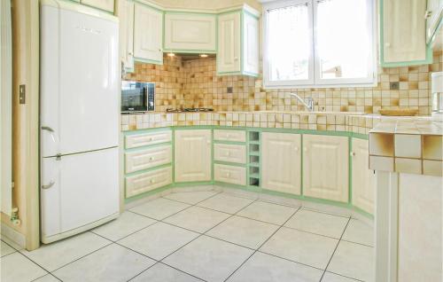 une cuisine avec des armoires blanches et un réfrigérateur blanc dans l'établissement Three-Bedroom Holiday Home In La Tranche Sur Mer, à La Tranche-sur-Mer