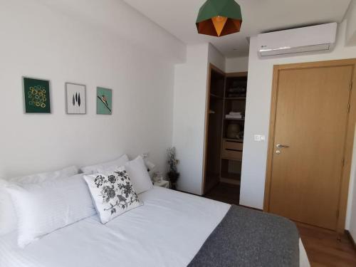 una camera da letto con letto, lenzuola e cuscini bianchi di Superbe appart cosy au centre de Casa+Free Parking a Casablanca