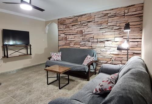 uma sala de estar com um sofá e uma parede de pedra em Apartamentos Los Robles em Alcalá del Júcar