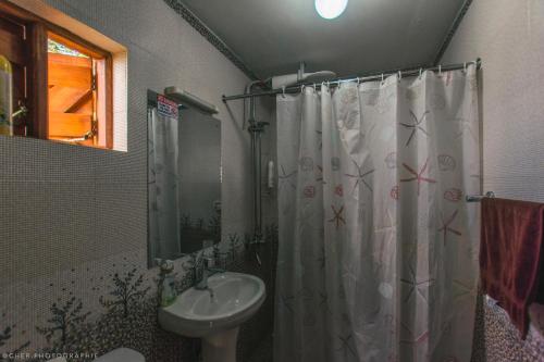 a bathroom with a shower curtain and a sink at The Wonky House in Timau