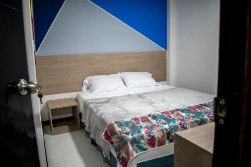 a small bedroom with a bed with a blue wall at Hotel Santo Tomas Bogota in Bogotá