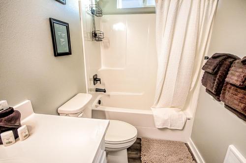 a white bathroom with a toilet and a bath tub at Wave Crest Cottage in Westport