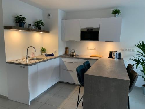 une cuisine avec des armoires blanches et un comptoir dans l'établissement La Légende, 2 pièces avec parking privé gratuit près du lac, à Annecy