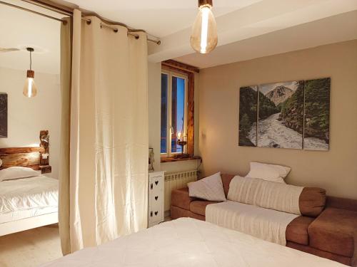 1 dormitorio con cama, sofá y ventana en GÎTE REDROOSTER HOME - Chaleur et bien-être au pied des 7 Laux - 4 ch - 2 sdb - Parking en Theys