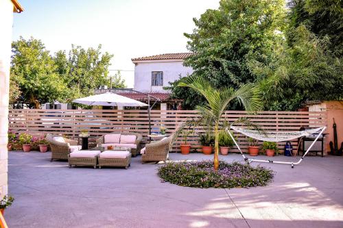 un patio con una hamaca, sillas y una valla en Villa Avly en Maleme