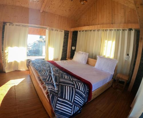 duże łóżko w pokoju z oknem w obiekcie Griffons Cafe and Stay w mieście Dharamsala