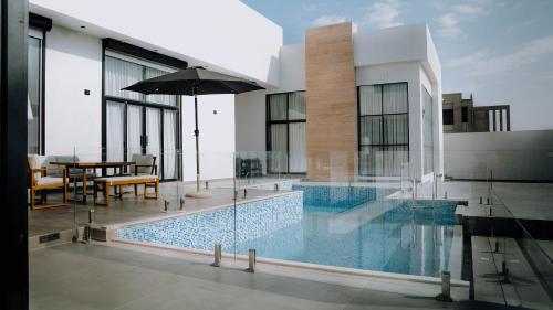 uma casa com uma piscina com uma mesa e um guarda-sol em Hummingbird Rak em Ras al-Khaimah