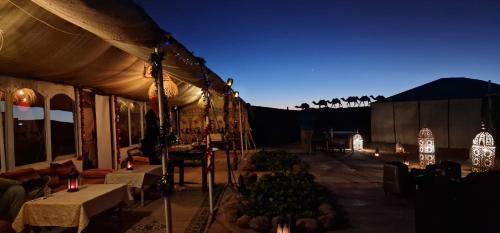 a tent with lights and tables and chairs at night at Fabulous luxury camp in Merzouga