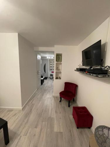 un salon avec une chaise rouge et une télévision dans l'établissement Au cœur des Vosges, à Saint-Étienne-lès-Remiremont