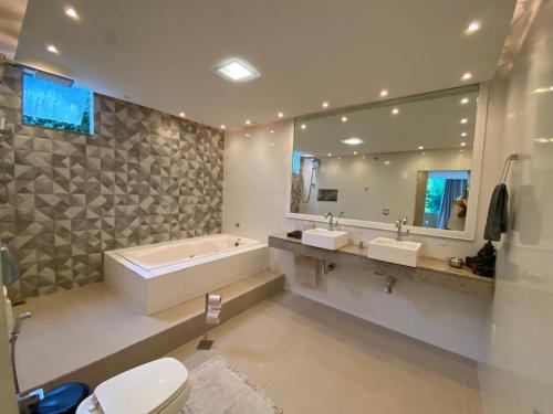 a bathroom with a tub and two sinks and a mirror at Casa na Praia Norte da ilha in Florianópolis