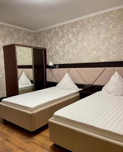 a bedroom with two beds and a mirror at Diar in Atyrau