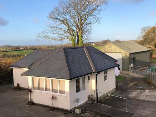 a small white house with a black roof at Cottage near Caernarfon, Gwynedd in Llanwnda