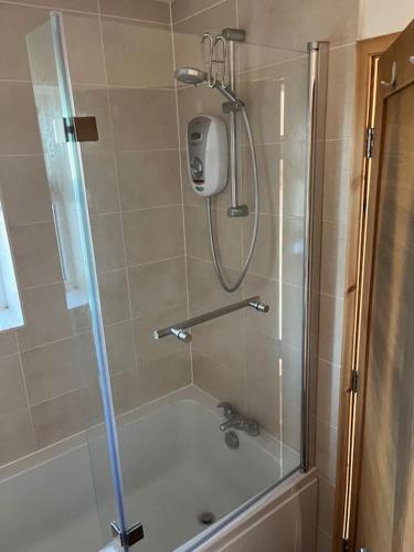 a shower in a bathroom with a glass door at Cottage near Caernarfon, Gwynedd in Llanwnda