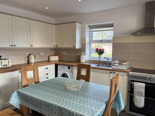 a kitchen with a table with a blue table cloth at Cottage near Caernarfon, Gwynedd in Llanwnda