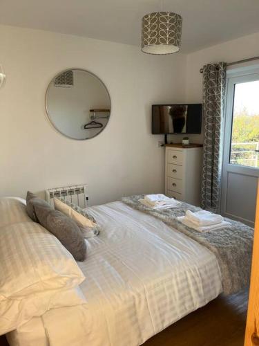 a bedroom with a bed with a mirror and a window at Cottage near Caernarfon, Gwynedd in Llanwnda