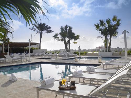 a resort pool with lounge chairs and palm trees at Grand Beach Hotel Surfside West in Miami Beach