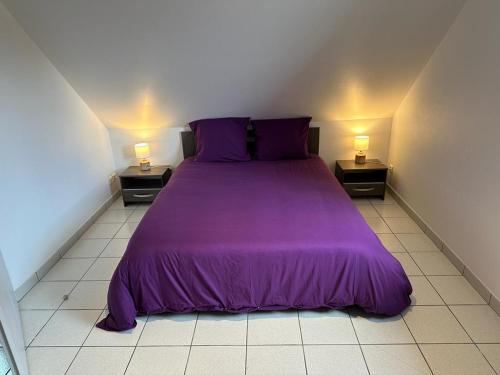 a purple bed in a small room with two lamps at Les cerisiers 
