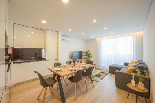 a kitchen and a living room with a table and chairs at Alameda 74 Luxury Apartment & Parking by Home Sweet Home Aveiro in Aveiro