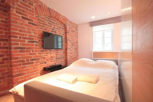 een slaapkamer met een bed met een bakstenen muur bij Modern & Resto Apartments in Krakau