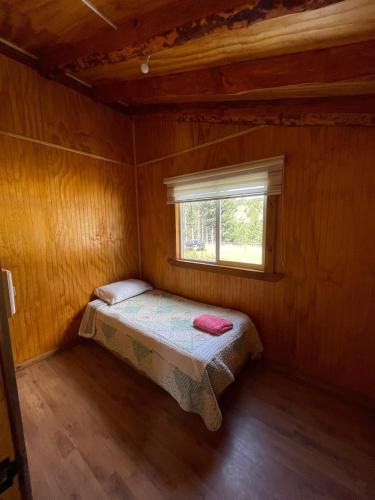 a small bedroom with a bed and a window at Cabaña la percha in Coihaique