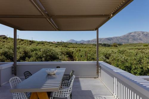 a porch with a table and chairs and mountains at Mikro Livadi Special Lodges - Has an Eco Salt water pool - 150m from the beach in Episkopí- Rethimno