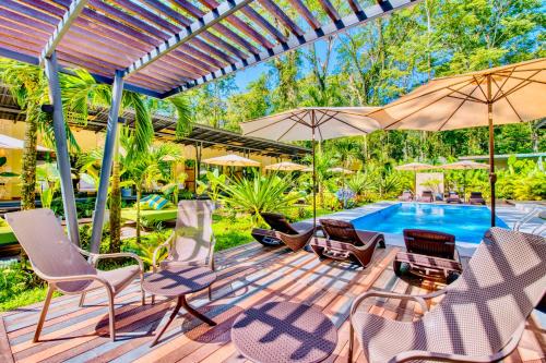 a deck with chairs and umbrellas next to a pool at Exôtico Beach Hotel in Puerto Viejo