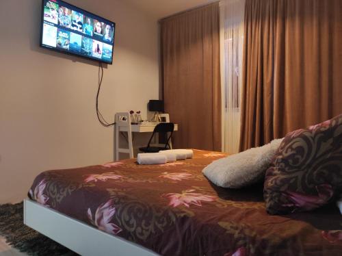 a bedroom with a bed with a desk and a television on the wall at Apartments Emi & Nini in Šibenik
