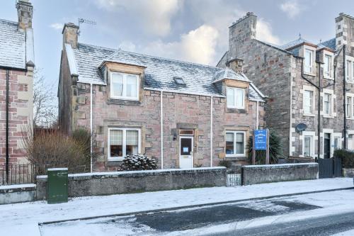 una vieja casa de ladrillo en una calle cubierta de nieve en mySTAYINN Strathblane House, en Inverness