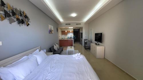 ein Schlafzimmer mit einem weißen Bett und ein Wohnzimmer in der Unterkunft Amazing Sea View Flat On The Beach in Ras al Khaimah