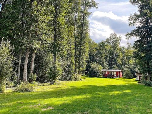 une grande pelouse avec une cabine rouge en arrière-plan dans l'établissement 5 person holiday home in LERDALA, à Lerdala