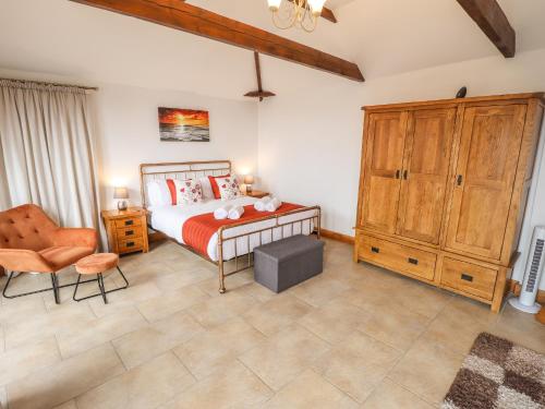 a bedroom with a bed and a wooden cabinet at Barn Cottage in Alford